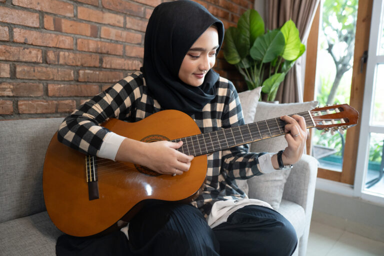 beautiful muslim woman play guitar while staying home